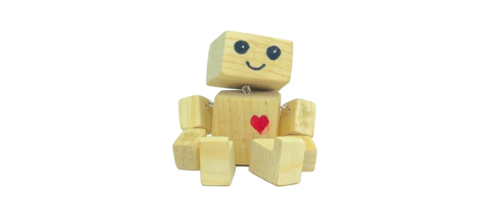 Rappresentazione giocosa di un robot in legno con un sorriso e un cuore, simbolo dell'evoluzione amichevole dei chatbot.